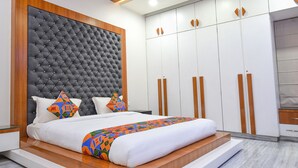 Een moderne slaapkamer met een gestoffeerd hoofdeinde, een groot bed met kleurrijke kussens, en een garderobe met verticale handgrepen.