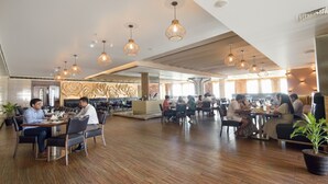 Un restaurant spacieux doté d’un plancher en bois, de nombreuses tables et de luminaires suspendus.