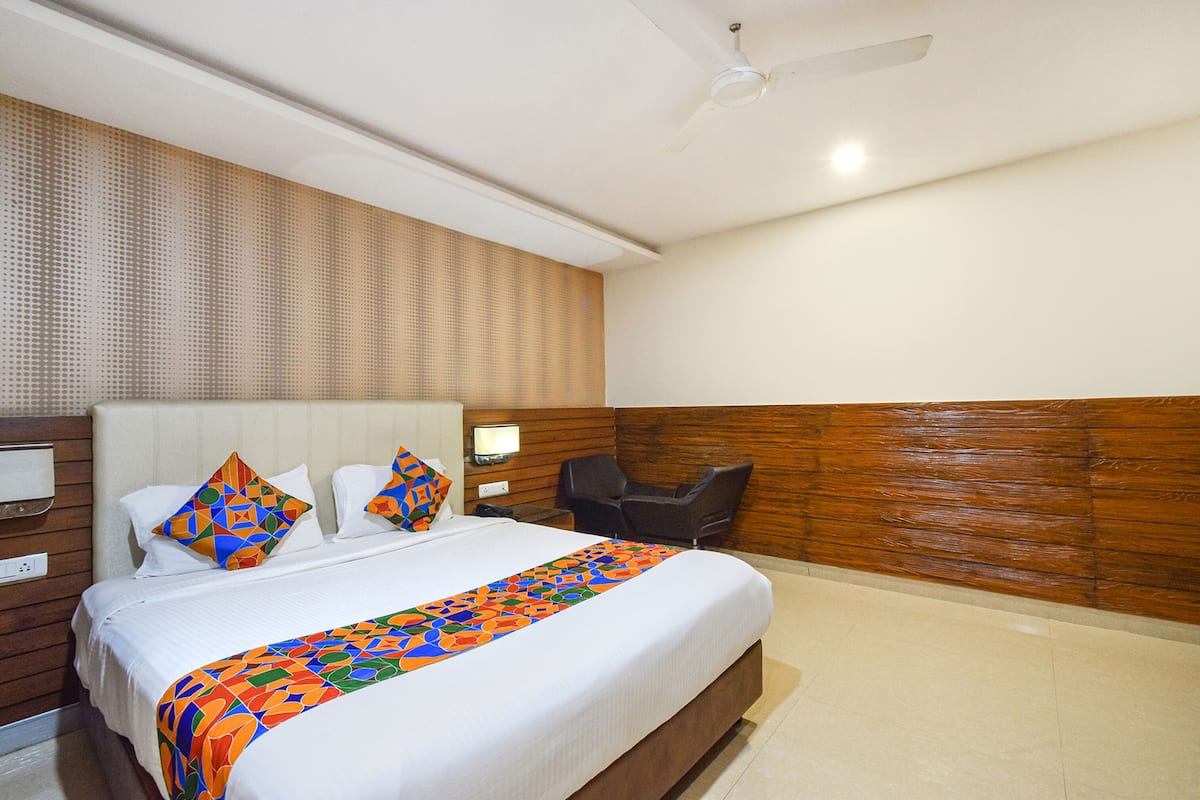 A hotel room with a large bed, a desk, a chair, and a ceiling fan.