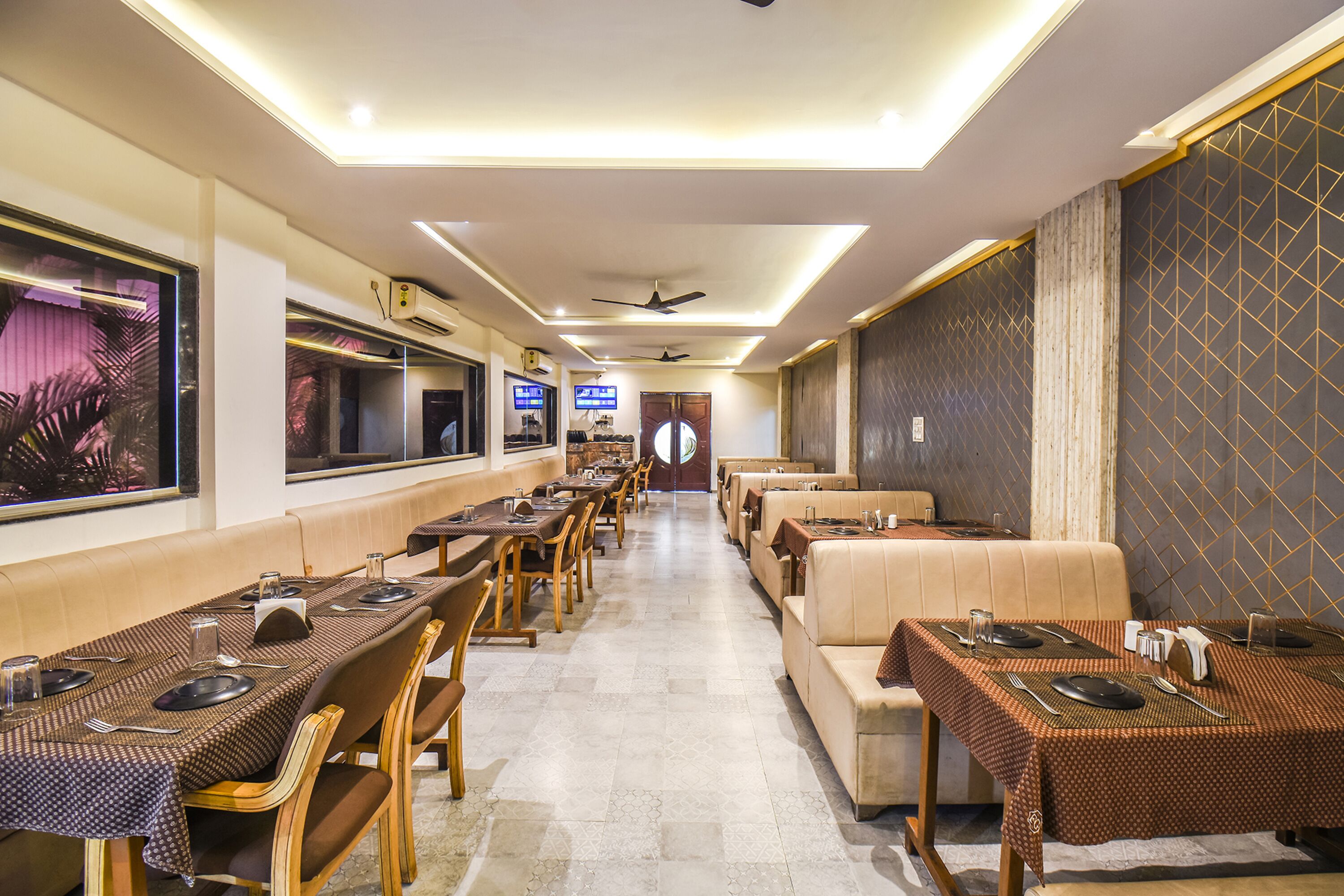 A restaurant with multiple dining tables and booths, ceiling fans, and wall-mounted televisions.