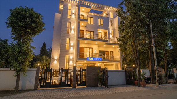 A multi-story hotel with a modern design, featuring balconies and a well-lit entrance. - Fabhotel New Journey Hospitality (Gurugram)
