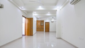 A spacious hallway with a tiled floor, wooden doors, and recessed lighting. - Fabhotel New Journey Hospitality (Gurugram)