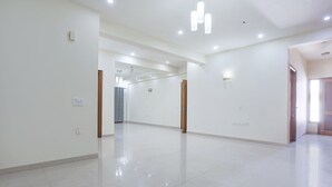 A spacious, well-lit hallway with white walls and a tiled floor, leading to multiple doors. - Fabhotel New Journey Hospitality (Gurugram)