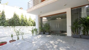 A modern outdoor patio area with potted plants and a glass door entrance. - Fabhotel New Journey Hospitality (Gurugram)