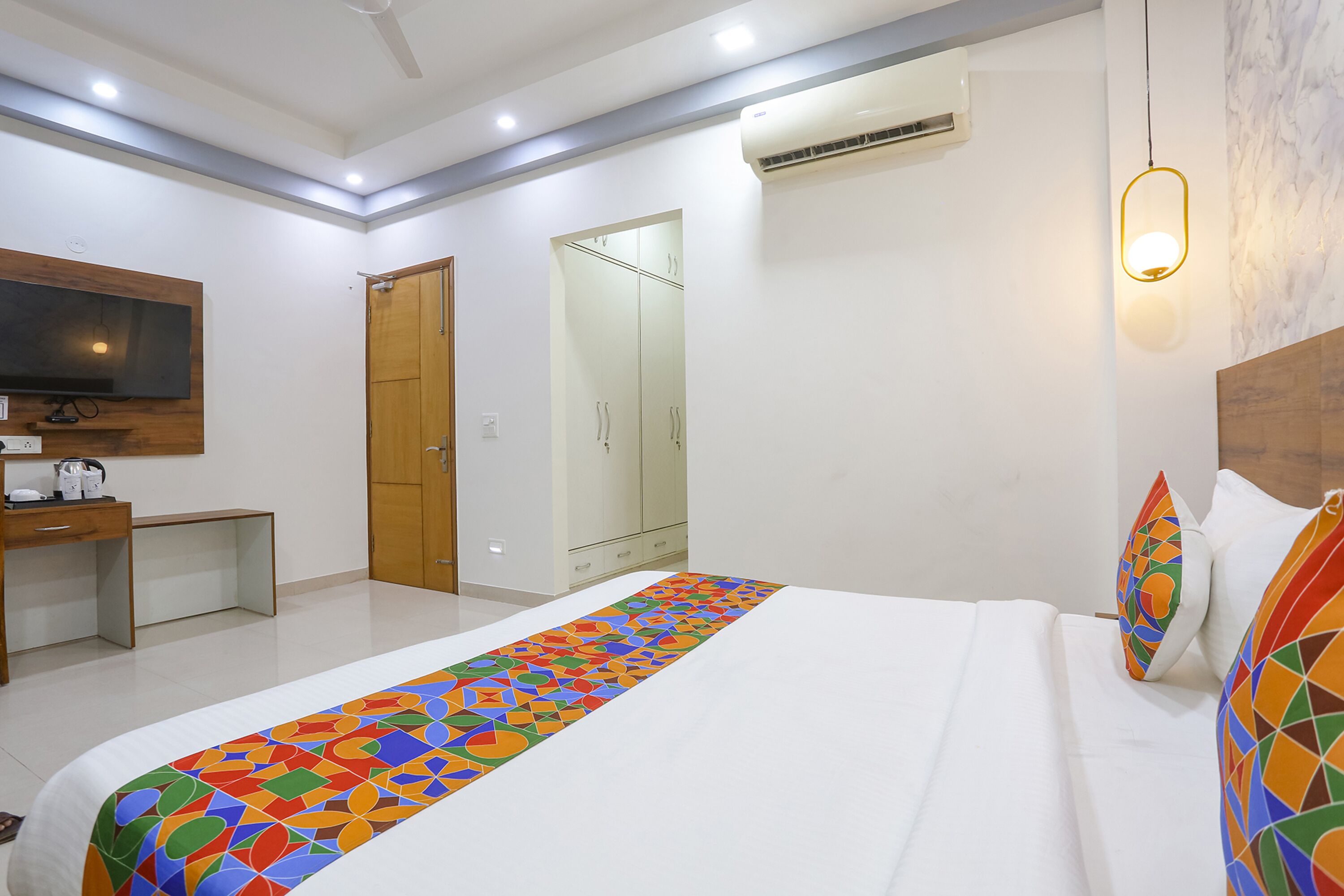 Una habitación de hotel con una cama, un escritorio, un televisor y un armario.