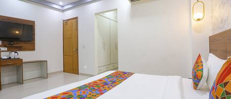 Una habitación de hotel con una cama, un escritorio, un televisor y un armario.