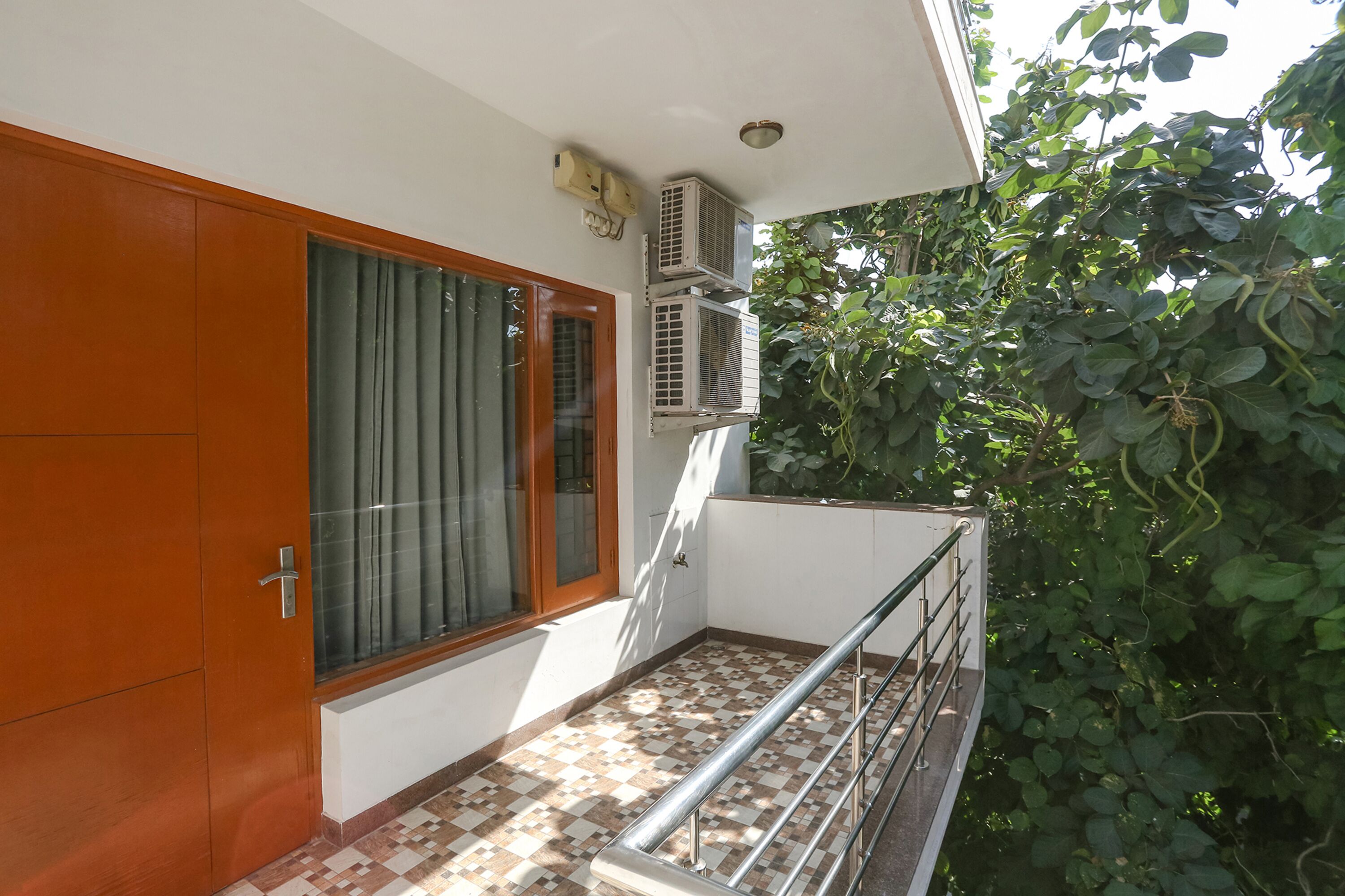 A balcony with a checkered floor, a wooden door, and air conditioning units.
