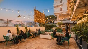 Un espace extérieur aménagé avec des tables, des chaises, des guirlandes lumineuses et de la verdure.