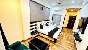 A modern hotel room with a bed, a TV, a small seating area, and a window. - Fabhotel Sky Heights (Haridwar)