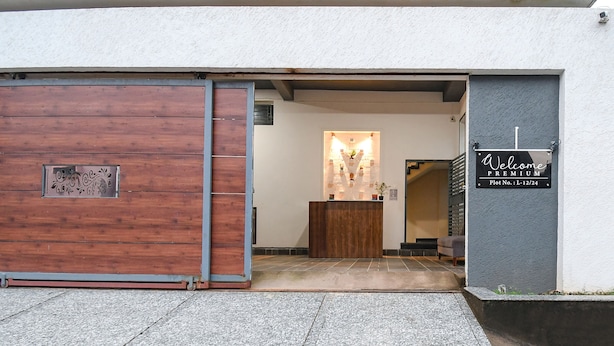 A hotel entrance with a wooden door, a reception desk, and a sign indicating 'Welcome Premium Plot No. L-12/24'. - Fabhotel Welcome Premium (Bhubaneshwar)