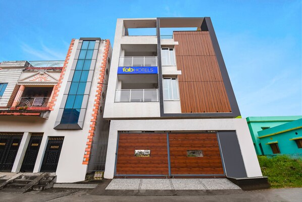 Un hôtel moderne avec une enseigne bleue, une façade en bois et un grand portail de garage.