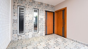 A hallway with patterned floor tiles, a wooden door, and a mirror on the wall. - Fabhotel Welcome Premium (Bhubaneshwar)