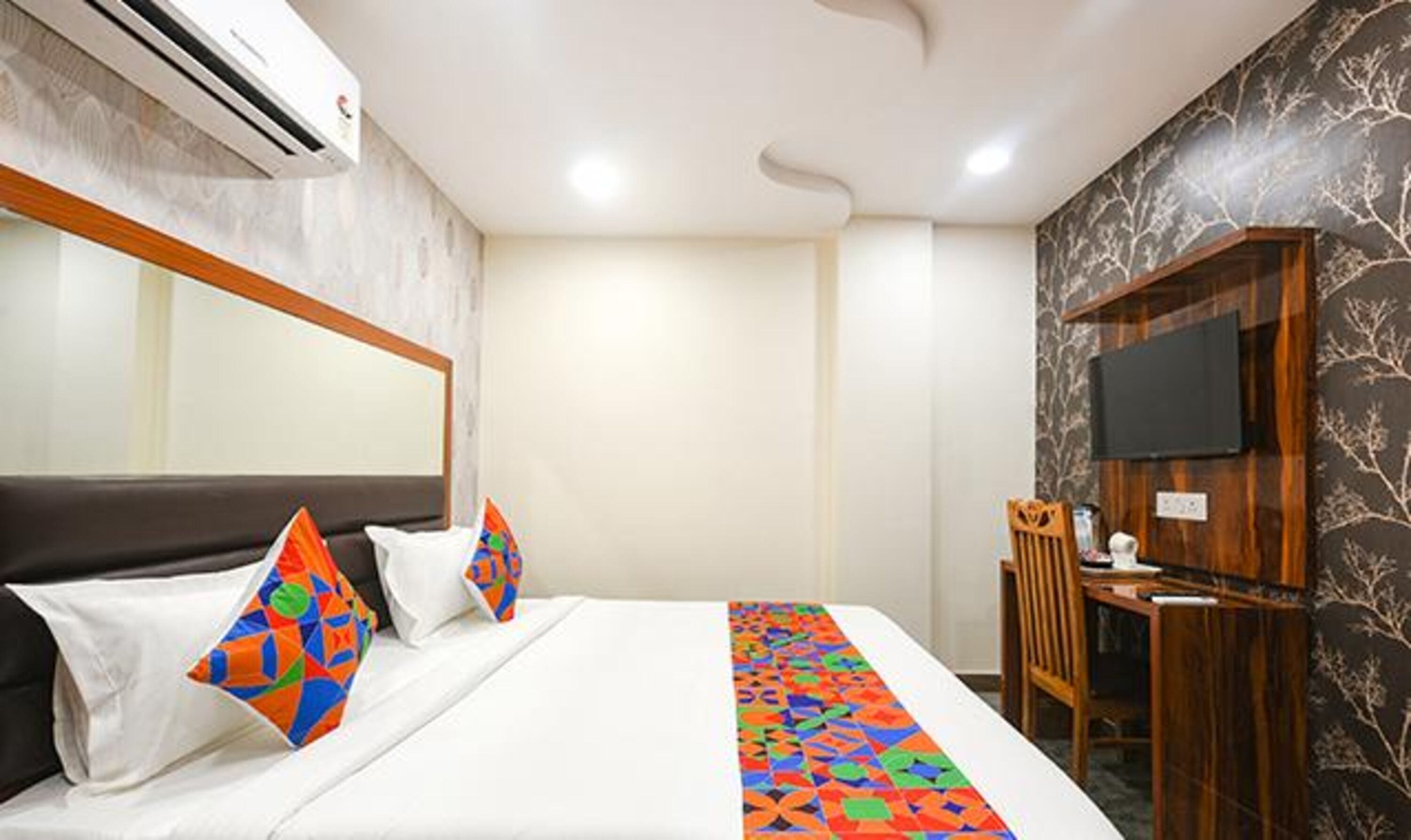 A hotel room with a bed, a TV, and a desk.