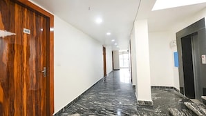 Un pasillo con una puerta de madera marcada con el número "403", paredes blancas y suelo de mármol.