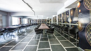 Un'ampia sala da pranzo con lunghi tavoli e sedie, soffitti alti e pannelli decorativi alle pareti.