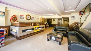 Un'area della reception di un hotel, con scrivania, orologio e una scala.