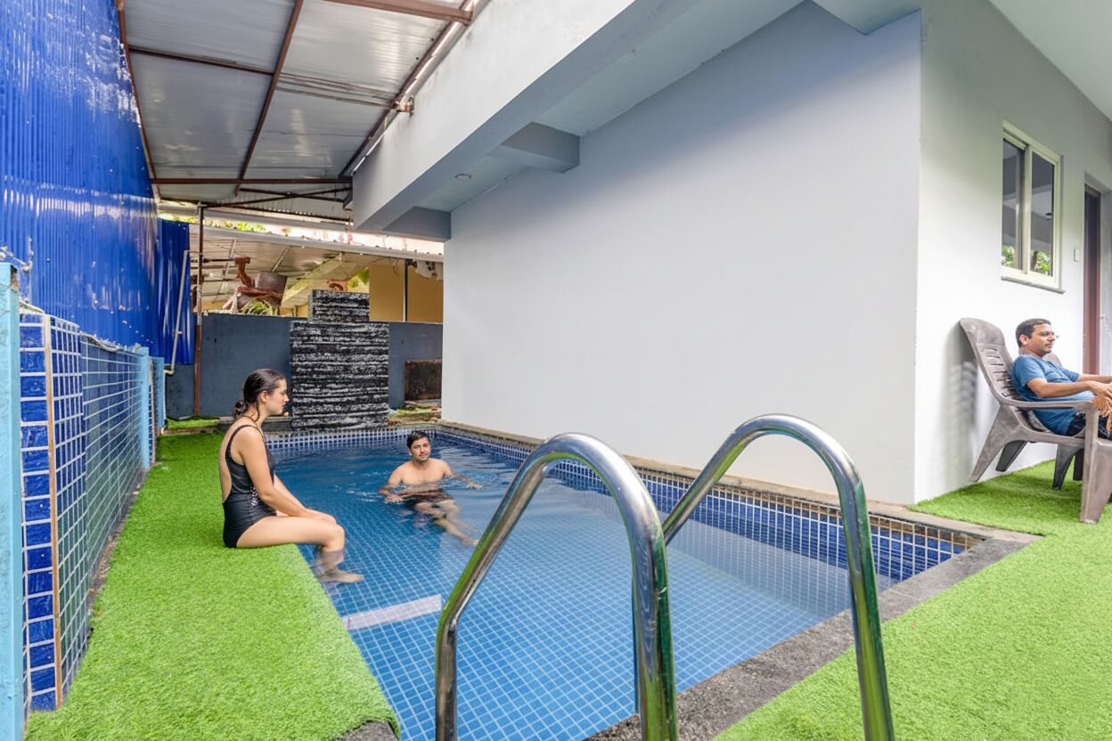 Ein Hallenbad mit Kunstgrasanlage, einer Metallleiter und einer Person, die am Pool sitzt.