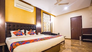 Une chambre d’hôtel avec un grand lit, un ventilateur de plafond, un appareil de climatisation, une fenêtre décorative et une porte.