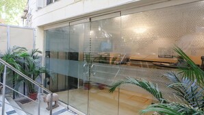 A modern building with a glass entrance, potted plants, and a metal railing. - FabHotel Comfort Residency II (Gurugram)