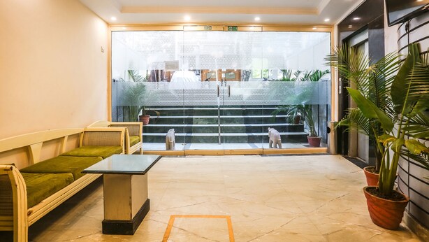 A reception area with a seating area, a reception desk, and a view of the entrance. - FabHotel Comfort Residency II (Gurugram)