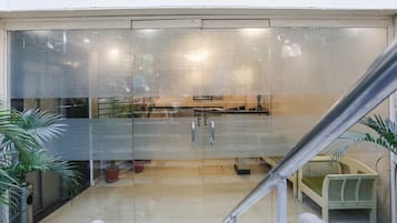 A modern interior with a glass partition, metal handles, and a staircase.