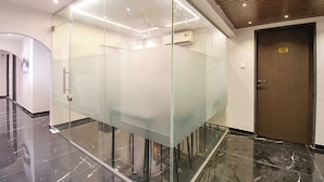 A modern conference room with glass partitions, a wooden ceiling, and a marble floor. - FabHotel Olive Suite (Pune)