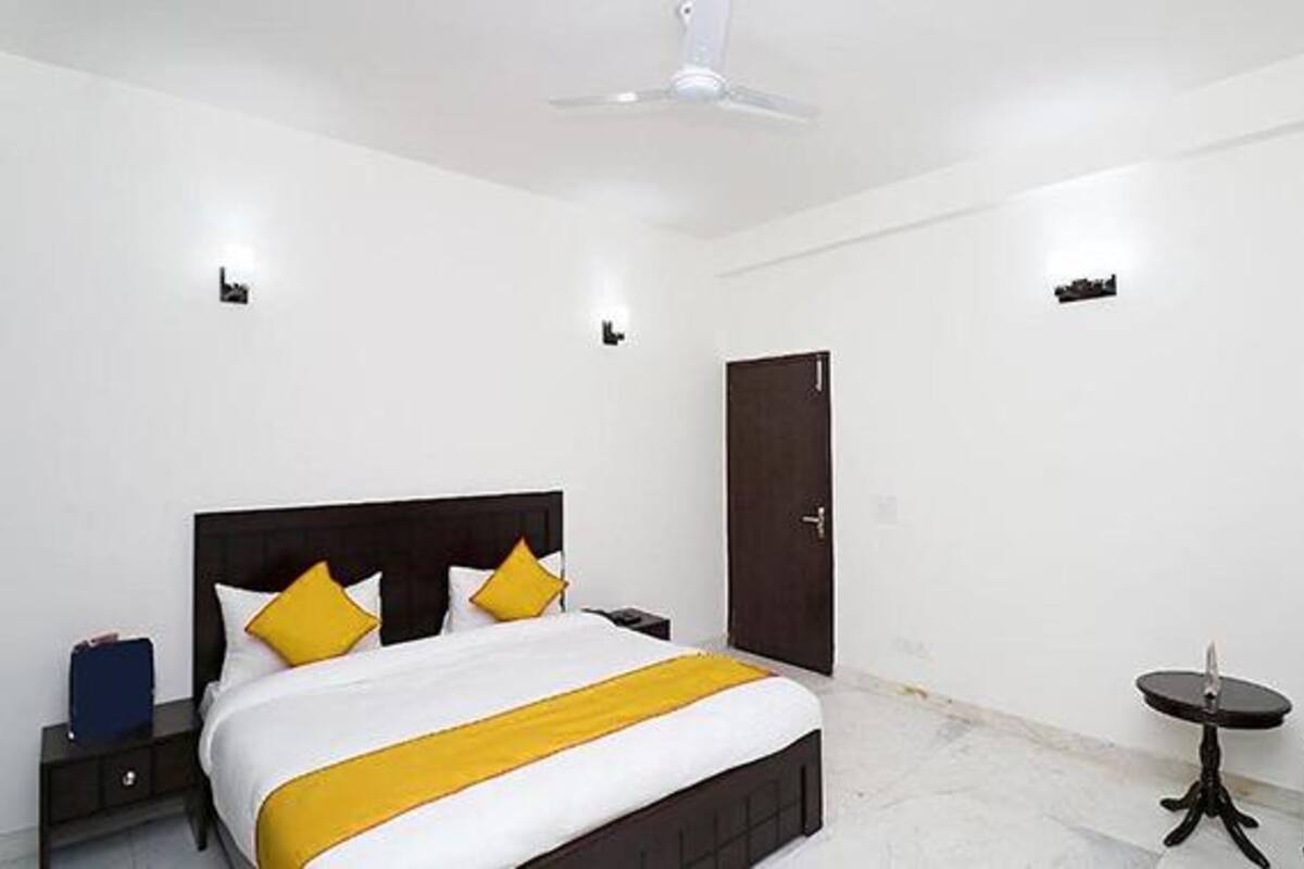 A hotel room with a bed, bedside tables, a chair, a small table, and a door.