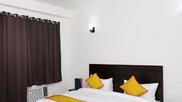 Una camera da letto con un letto, un comodino, una ventola a soffitto e una finestra con tende.