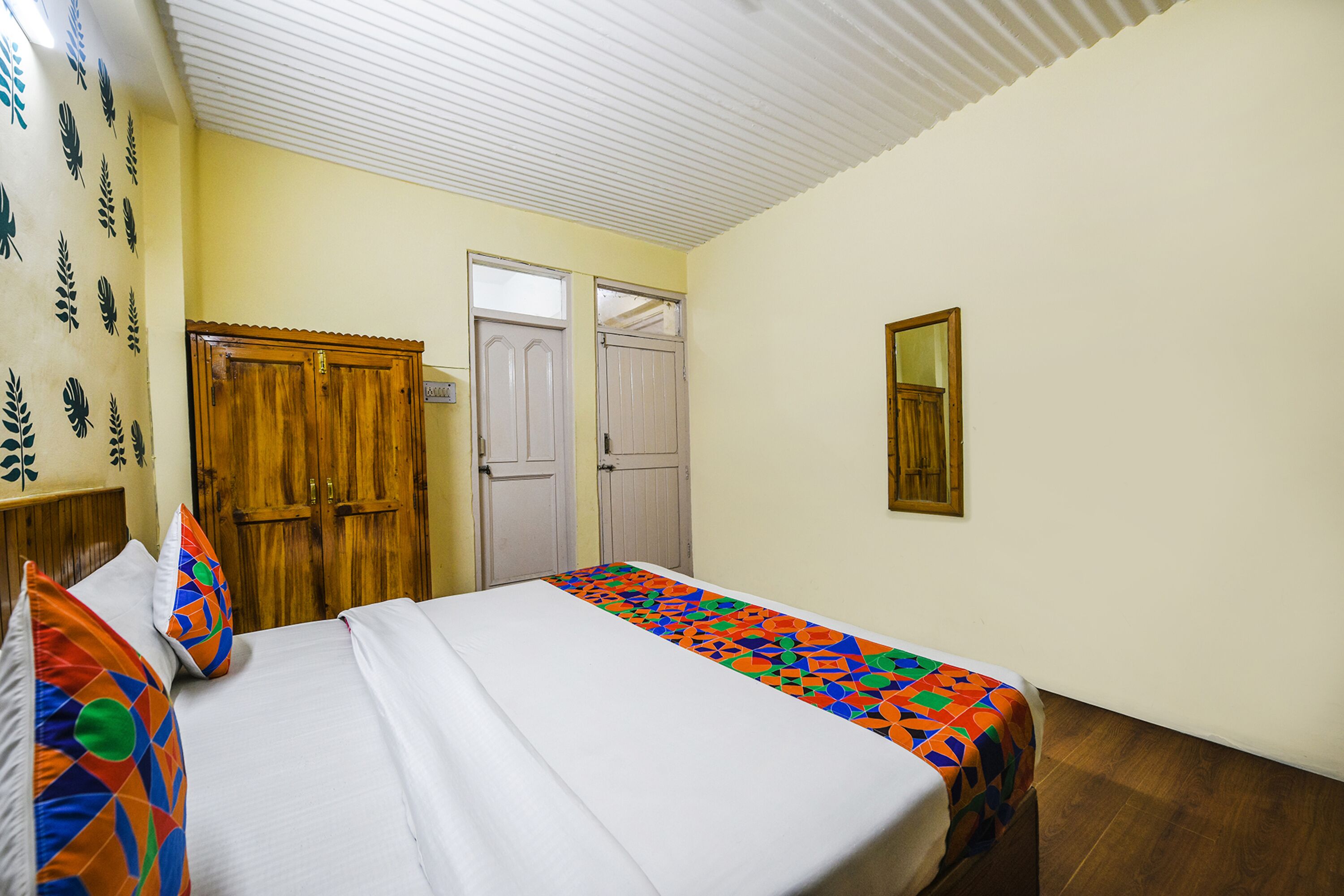 A hotel room with a bed, a wooden wardrobe, and a door.