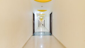 Un long couloir étroit, doté d’un sol réfléchissant et bordé de part et d’autre par une série de portes.