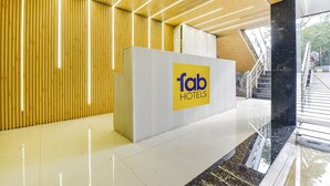 Un hall d'hôtel moderne, avec un panneau bien visible indiquant « fab hotels », un plafond en lambris de bois et un escalier menant aux étages supérieurs.