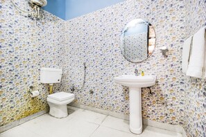 A bathroom with a mosaic tile wall, a toilet, a sink, and a mirror. - FabHotel Trubell Electronic City (Anekal)