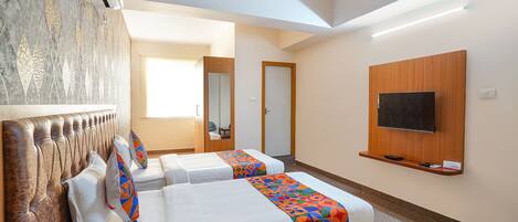A hotel room with two beds, a ceiling fan, a TV mounted on the wall, and a large mirror.