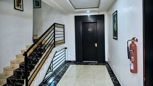 A staircase with black and gold railings, a fire extinguisher mounted on the wall, and a door labeled "FLAT 411". - Executive Luxury Room - Sleeps 2 - Pool - Gym (Lagos)