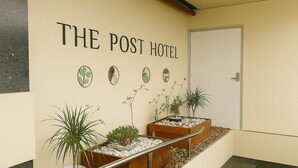 A hallway with a sign reading "THE POST HOTEL" and several potted plants along the wall. - The Post Hotel (Porirua)