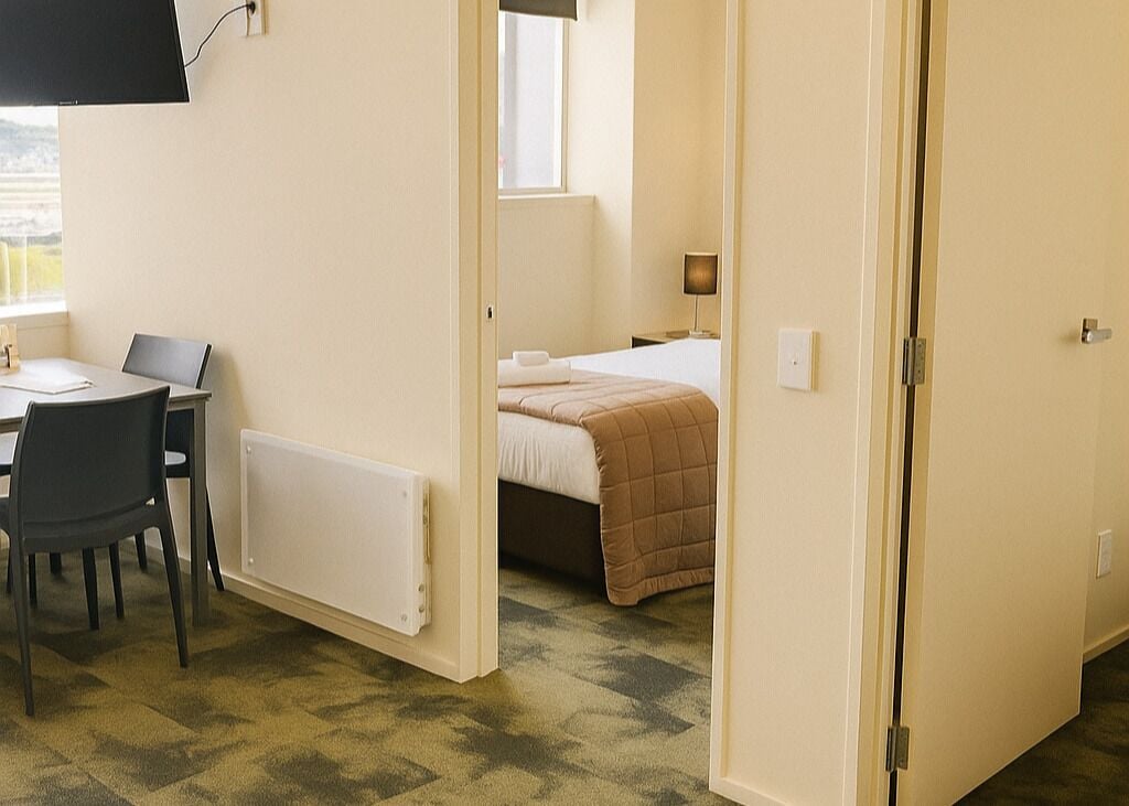 A hotel room with a bed, a desk with a chair, and a window.