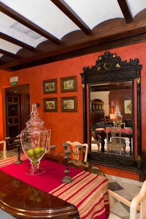 A dining area with a table set for two, a large mirror, and framed pictures on the wall. - Hotel Soho Boutique Vistahermosa (El Puerto de Santa Maria)