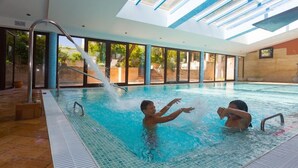 An indoor swimming pool with clear glass walls, a tiled floor, and a water fountain. - Hotel Soho Boutique Vistahermosa (El Puerto de Santa Maria)