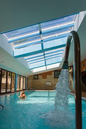 Piscina interna com claraboias e uma fonte visível.