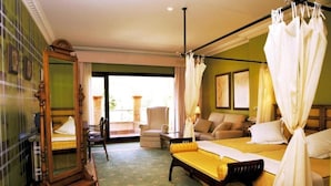 A hotel room with a large bed, a sitting area with a sofa and armchairs, a wooden chair, a large mirror, and a balcony with a view. - Hotel Soho Boutique Vistahermosa (El Puerto de Santa Maria)