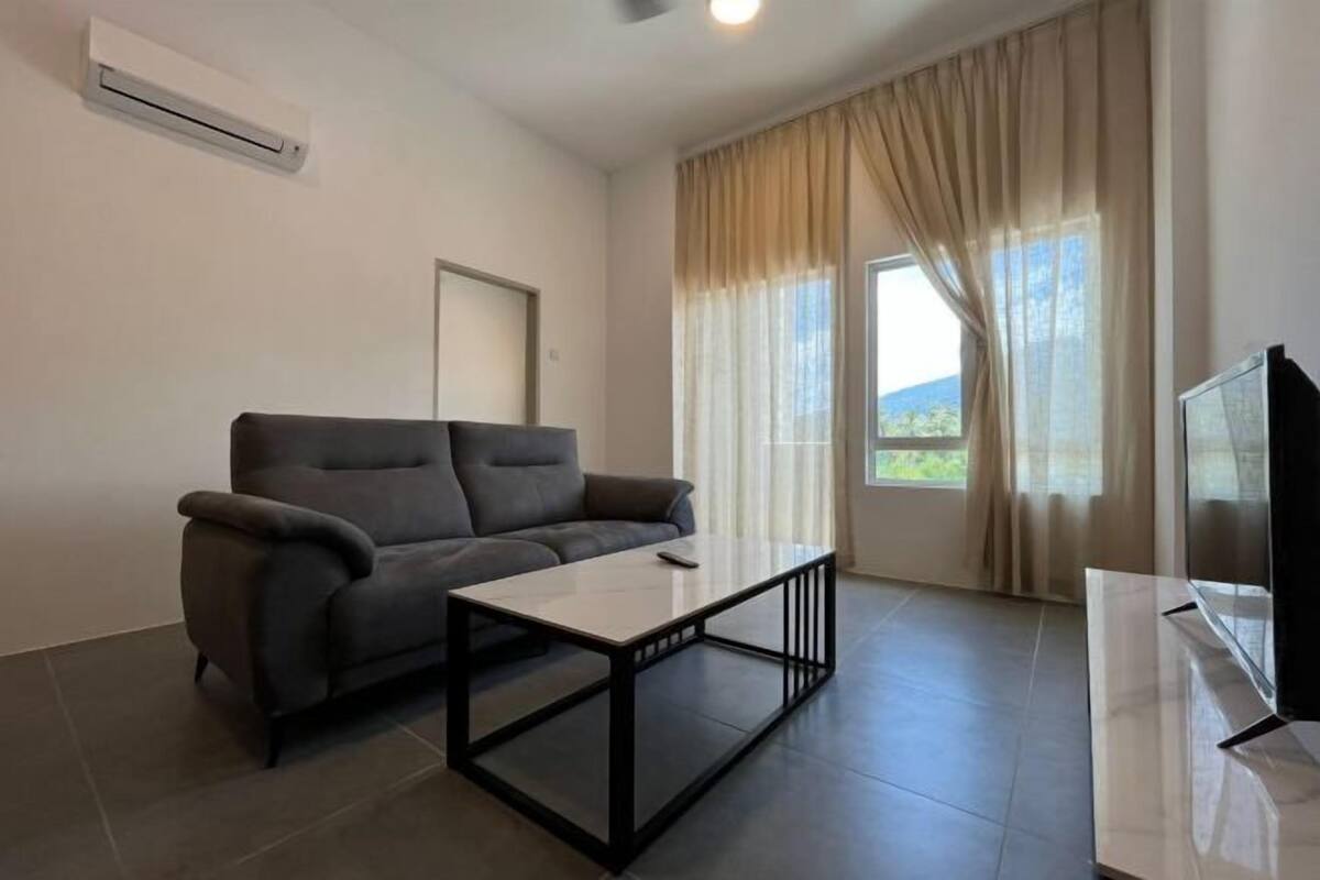 A modern living room with a sofa, a coffee table, a TV, and a window with curtains.