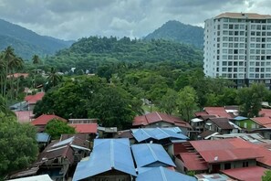 A residential area with houses, a tall building, and mountains in the background. - Langkawi - Simfoni Beliza (Langkawi)