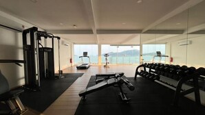 Et fitnesscenter med træningsudstyr, løbebånd og havudsigt.