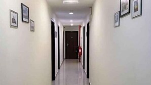 A corridor with framed pictures on the walls, a door at the end, and a red object on the floor. - Chariton Hotel Skudai Kiri (Johor Bahru)