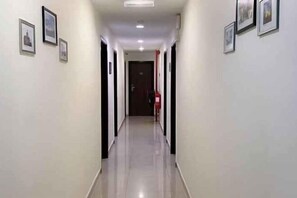 A corridor with framed pictures on the walls, a door at the end, and a red object on the floor. - Chariton Hotel Skudai Kiri (Johor Bahru)