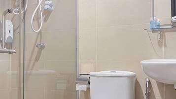 A bathroom with a glass shower enclosure, a toilet, and a sink.