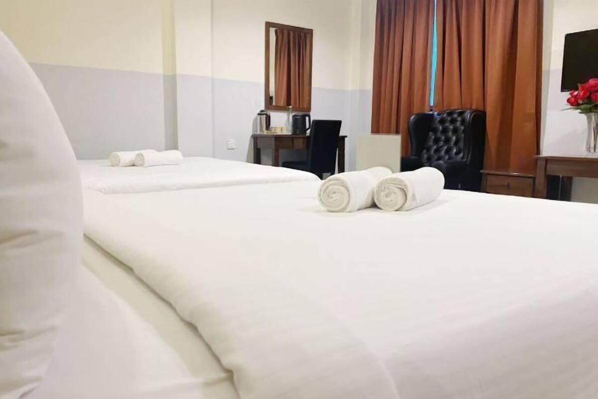Una habitación de hotel con dos camas, un escritorio, una silla y un espejo.