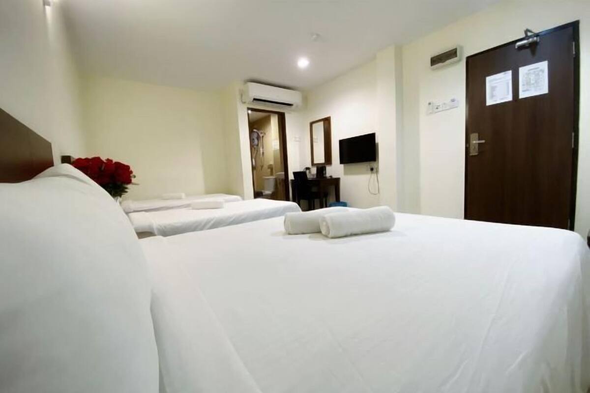 Habitación de hotel con dos camas, un escritorio, una silla, un televisor y una puerta con un aviso.