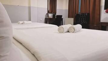 A hotel room with two beds, a desk, and a chair.