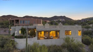 A modern house with a patio area, surrounded by desert vegetation and hills in the background. - Casa Milagro - A designer desert retreat! (Tucson)